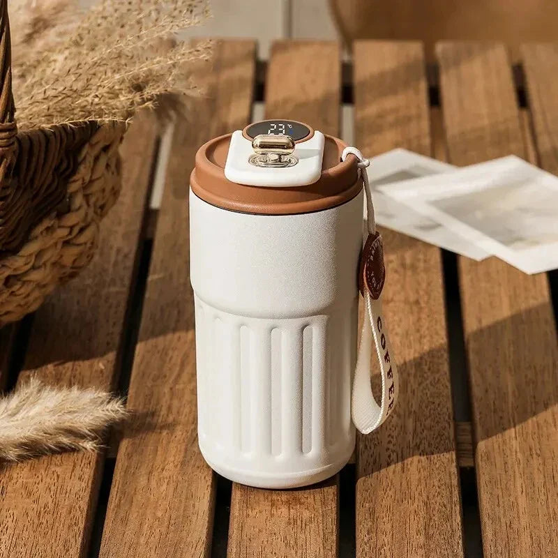 Tasse isotherme intelligente affichant la température, posée sur un bureau mobile avec ordinateur portable