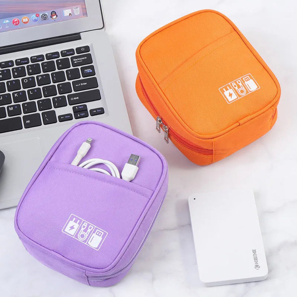 Étui de voyage pour câbles et chargeurs posé sur un bureau blanc près d'un laptop