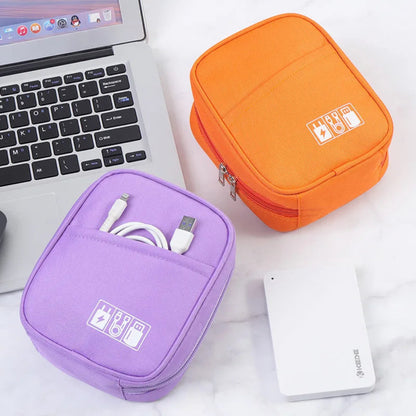 Étui de voyage pour câbles et chargeurs posé sur un bureau blanc près d'un laptop